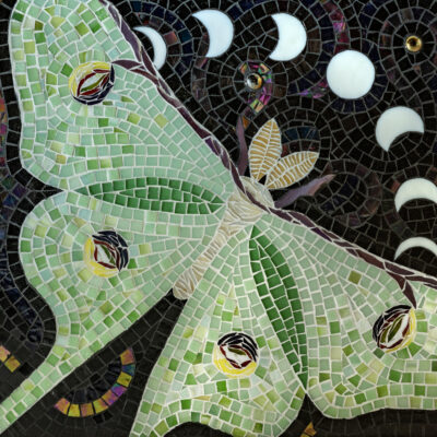 moth and moons made out of glass and grout on wood